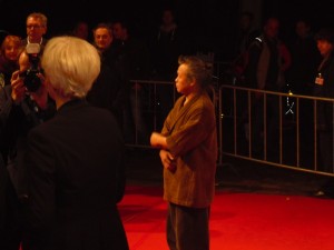 Kim Ki-Duk auf dem roten Teppich; im Hintergrund Laudator Feridun Zaimoglu